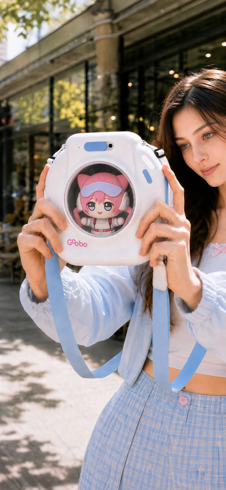 A smiling woman holding the GOOBO smart ita bag with a plush peeking out of its clear window on a sunny city rooftop